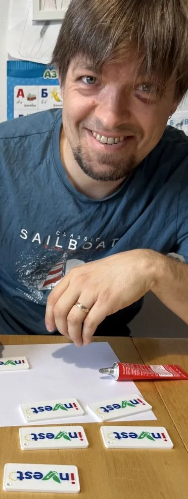 Iurii at a table with real printed inVest keychain prototypes