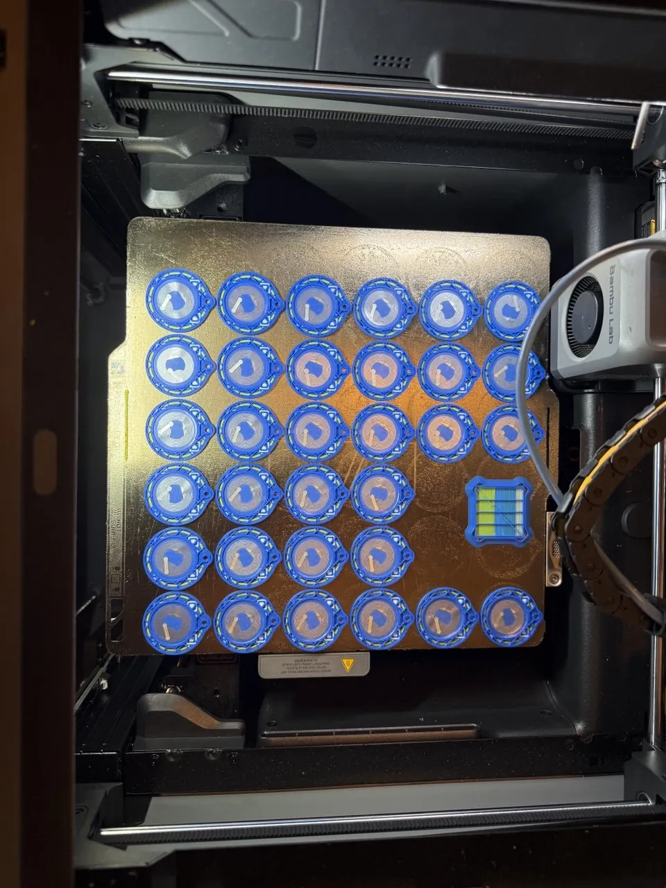 Blue round multicolor keychains being printed in a batch inside our machine